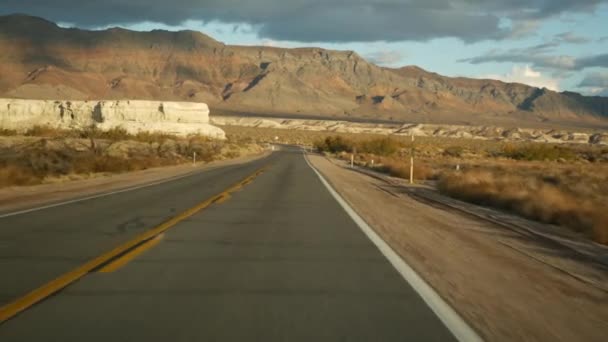 Viaje por carretera, conduciendo auto desde Death Valley a Las Vegas, Nevada, EE.UU. Hacer autostop viajando por América. Viaje por carretera, atmósfera dramática, montaña al atardecer y desierto de Mojave. Vista desde el coche — Vídeo de stock