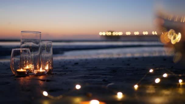 Luces de llama de vela en vidrio, fecha romántica playa por las olas del océano, mar de verano. Luz de las velas en la arena. — Vídeos de Stock