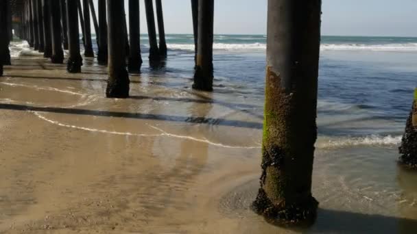 Trähögar under piren i Kalifornien USA. Pilar, pyloner eller pelare under bron. Havsvågor — Stockvideo