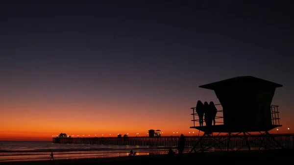 Jonge tiener meisjes silhouetten, badmeester wachttoren, vrienden op Stille Oceaan strand, Californië Verenigde Staten. — Stockfoto