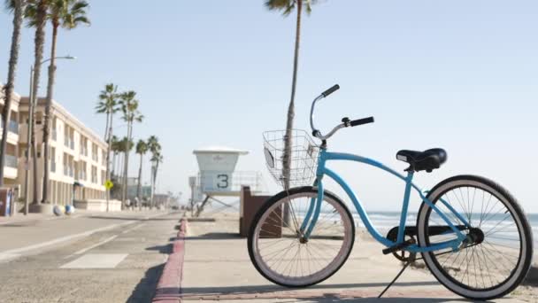 Bicicleta de crucero en bicicleta por la playa del océano, costa de California EE.UU.. Ciclo de verano, cabaña salvavidas y palmera — Vídeos de Stock
