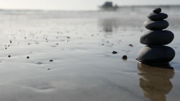 Équilibre rocheux sur la plage océanique, pierres empilées par les vagues d'eau de mer. Pyramide de galets sur le rivage sablonneux — Video