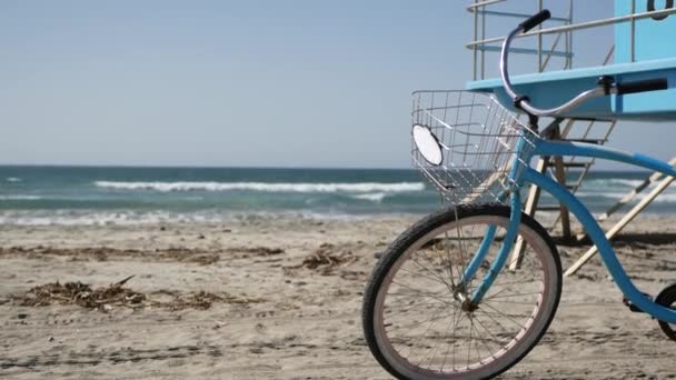 Bicicleta crucero en bicicleta por la playa del océano costa de California EE.UU.. Playa de verano. Ciclo por torre de salvavidas — Vídeo de stock