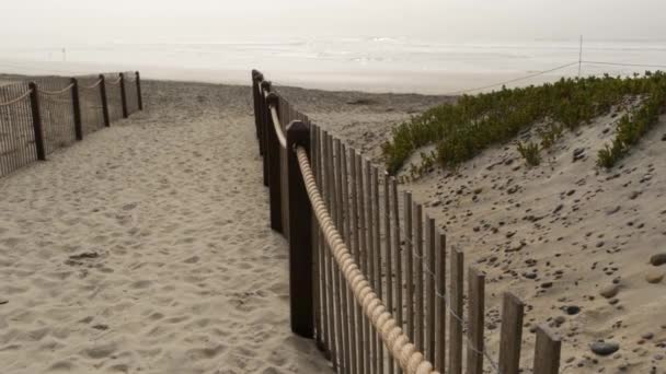 Recinzione di legno picchetto, spiaggia sabbiosa nebbiosa, California USA. Oceano Pacifico costa, nebbia nebbia sulla riva del mare. — Video Stock