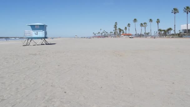 Palm trees on white sandy beach, ocean sea coast in California USA. Lifeguard tower, watchtower hut. — Stock Video
