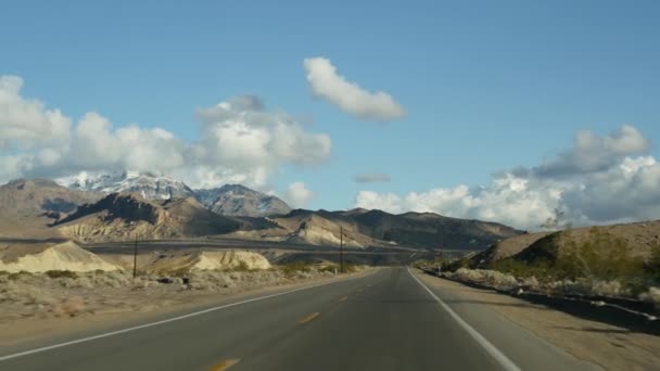 开车从死谷到美国内华达州拉斯维加斯的公路旅行。搭便车在美国旅行。公路旅行，戏剧性的氛围，云彩，高山和莫哈韦沙漠荒原。从车上看 — 图库视频影像
