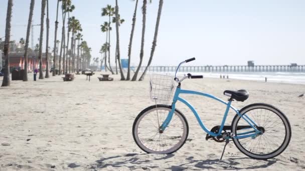 Bicicleta de cruzador de bicicleta por praia oceânica, costa da Califórnia EUA. Ciclo de verão, cabana salva-vidas e palmeira — Vídeo de Stock