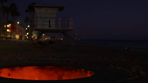 Hoyo de fogata en California USA. Fuego de campamento en la playa del océano crepúsculo, llama de hoguera por las olas de agua de mar. — Vídeos de Stock