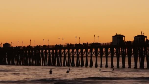 Pier silhuett vid solnedgången, Kalifornien USA, Oceanside. Surfinganläggning, tropisk havsstrand. Surfare väntar på våg. — Stockvideo