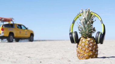 Kulaklıklı ananas, kumlu okyanus sahili. Tropik yaz egzotik meyveleri. Ananas kıyıda.