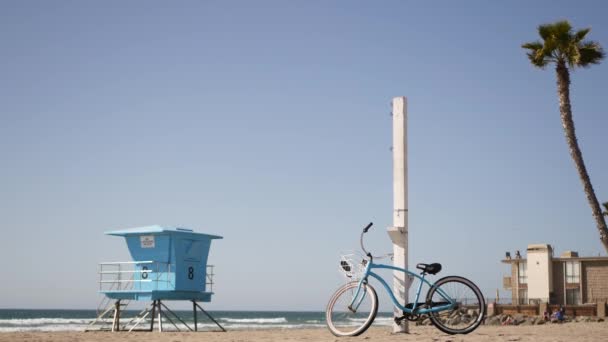 Cykel cruiser cykel vid havet stranden Kalifornien kust USA. Sommarstrand. Cykel med livräddartorn — Stockvideo