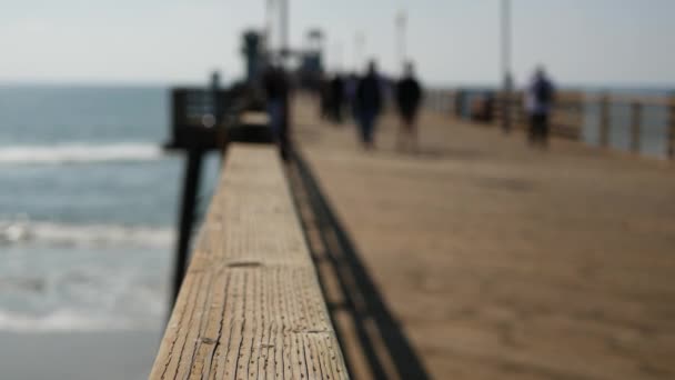 Píer de madeira beira-mar calçadão, Califórnia praia EUA. Oceano desfocado, ondas do mar. Pessoas andando. — Vídeo de Stock