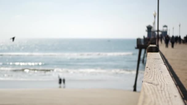 Fa móló vízparti sétányon, California Beach USA. Elmosódott óceán, tengeri hullámok. Sétáló emberek. — Stock videók