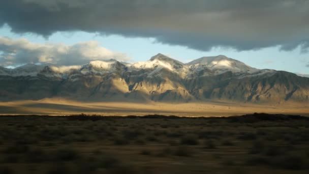 Viaje por carretera, conduciendo auto desde Death Valley a Las Vegas, Nevada, EE.UU. Hacer autostop viajando por América. Viaje por carretera, atmósfera dramática, montaña al atardecer y desierto de Mojave. Vista desde el coche — Vídeos de Stock
