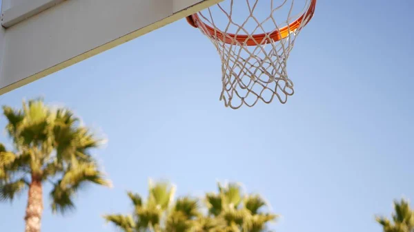 Orange hoop, net and backboard for basket ball game. Basketball court outdoors.