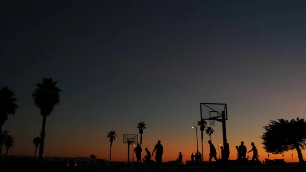 Pessoas na quadra de basquete jogando basquete jogo de bola. Pôr do sol na praia, Califórnia — Fotografia de Stock