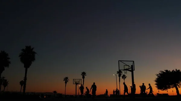 Basketbol sahasındaki insanlar basketbol oynuyor. Kaliforniya sahilinde gün batımı — Stok fotoğraf