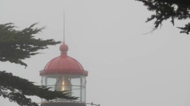 Eski deniz feneri mercekleri parlıyor, sisli yağmurlu hava. Aydınlatılmış Beacon USA