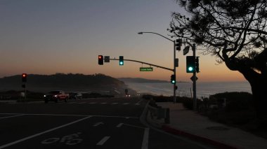 Trafik ışıkları, Pasifik kıyısı otoyolu, California. Alacakaranlıkta okyanus boyunca yolculuk