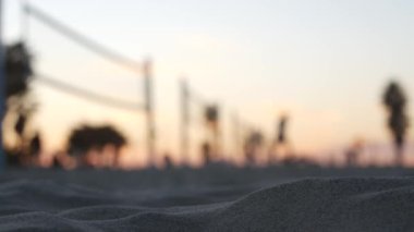 Plaj kortunda voleybol oynayan oyuncular, top ve net ile voleybol oyunu.