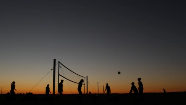 Die Silhouette des Volleyballnetzes auf dem Beach Court bei Sonnenuntergang, die Spieler an der kalifornischen Küste. — Stockvideo
