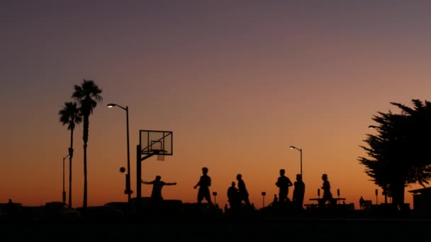 Hráči na basketbalovém hřišti hrají basketbal, západ slunce pláž, Kalifornie. — Stock video