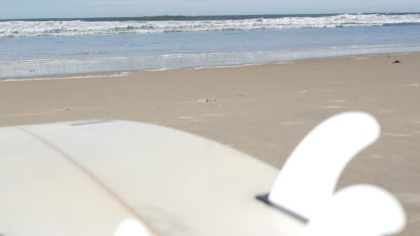 Surfboard for surfing lying on beach sand, California coast, USA. Oceánské vlny. — Stock video
