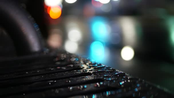 Reflexão de semáforos de carro no banco de parada de ônibus. Gotas de chuva de água em metal molhado. — Vídeo de Stock