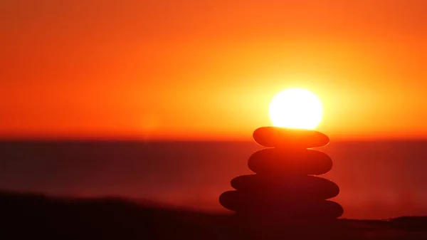 Stack of pebble stones, sandy ocean beach, sunset sky. Rock balancing by water. — Stock Photo, Image