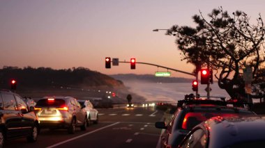 Trafik ışıkları, Pasifik kıyısı otoyolu, California. Alacakaranlıkta okyanus boyunca yolculuk