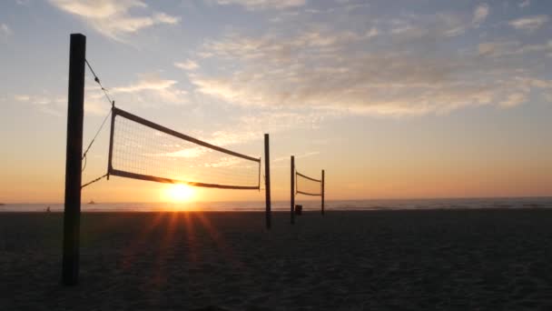 Sílhueta líquida de vôlei na quadra de esporte de praia ao pôr do sol, costa da Califórnia, EUA. — Vídeo de Stock