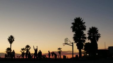 Basketbol sahasında basketbol oynayan oyuncular, günbatımı plajı, California.