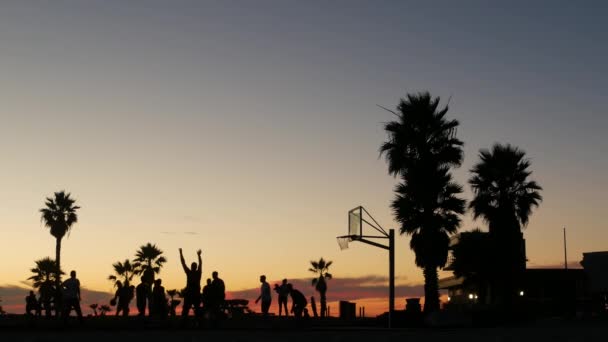 Players on basketball court playing basket ball game, sunset beach, California. — Stock Video