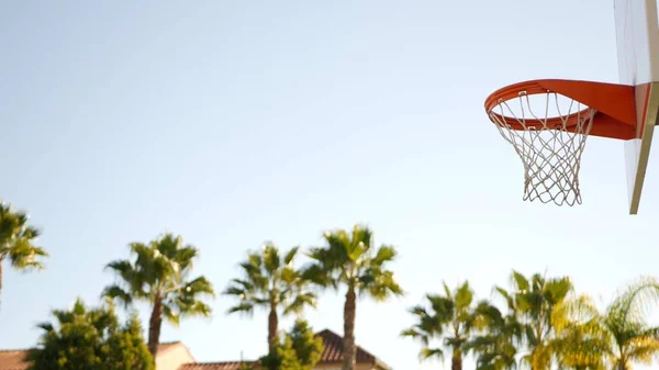 Orange hoop, net and backboard for basket ball game. Basketball court outdoors.