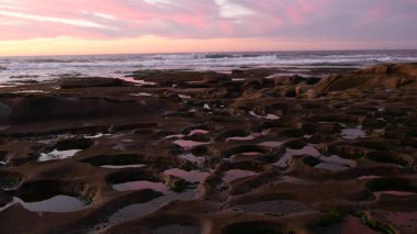 Kaliforniya 'da gelgit havuzu kaya oluşumu. Günbatımı gökyüzü yansıması suda.