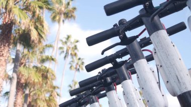 Sokak kaldırımına, palmiye ağaçlarına, Kaliforniya 'ya park edilmiş kiralık elektrikli scooter' lar..
