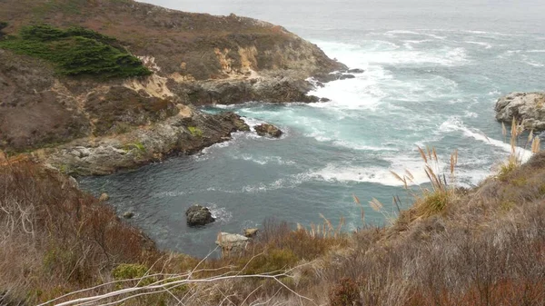 Rotsachtige grillige oceaan, mistig weer. Golven storten neer op het strand. Californië, Grote Sur.. — Stockfoto