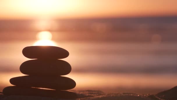 Stack of pebble stones, sandy ocean beach, sunset sky. Rock balancing by water. — Stock Video