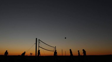 Gün batımında plaj kortunda voleybol net silueti, California sahilinde oyuncular.