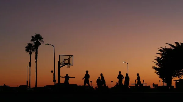 Hráči na basketbalovém hřišti hrají basketbal, západ slunce pláž, Kalifornie. — Stock fotografie