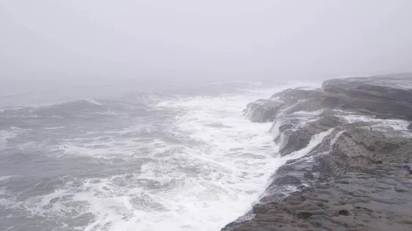 Mistig zeelandschap, golven die neerstorten op het strand in de mist. Stormachtig mistig weer — Stockfoto