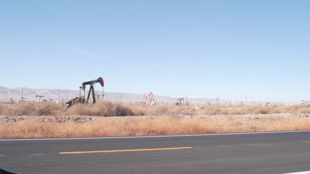 Jaquetas de bomba no campo de petróleo, EUA. Plataformas para extracção de fósseis brutos em poços de campos petrolíferos — Vídeo de Stock