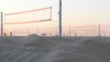 Plaj kortunda voleybol oynayan oyuncular, top ve net ile voleybol oyunu.