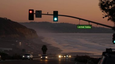 Trafik ışıkları, Pasifik kıyısı otoyolu, California. Alacakaranlıkta okyanus boyunca yolculuk