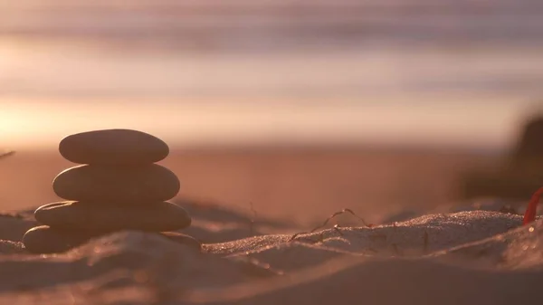 Kieselsteinhaufen, Sandstrand am Meer, Himmel bei Sonnenuntergang. Felsausgleich durch Wasser. — Stockfoto