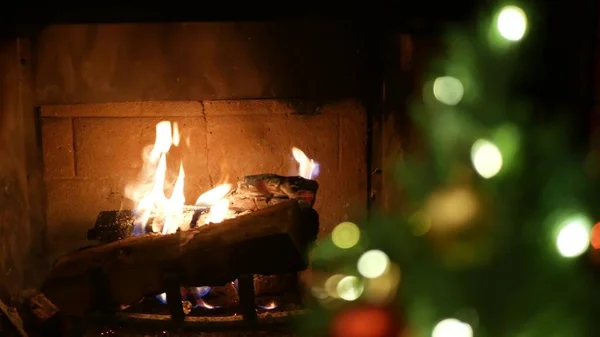Christmas tree lights by fire in fireplace, New Years Eve or Xmas decoration.