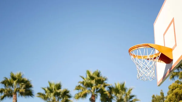 Basketball court outdoors, orange hoop, net and backboard for basket ball game.