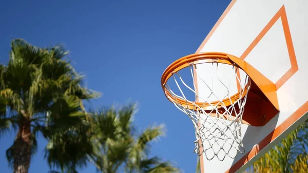 Basketball court outdoors, orange hoop, net and backboard for basket ball game.