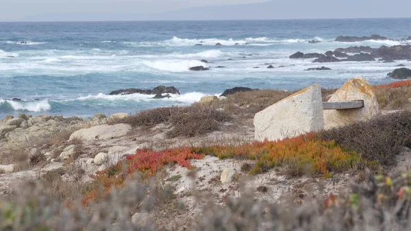 Costa oceânica rochosa, ondas do mar, Monterey Califórnia. Banco vazio de madeira. — Fotografia de Stock