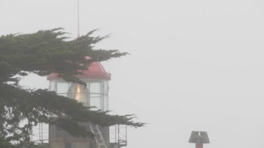 Eski deniz feneri mercekleri parlıyor, sisli yağmurlu hava. Aydınlatılmış Beacon USA